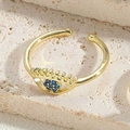 Detailed close-up of a gold Evil Eye ring with blue and clear zircon on a stone surface - Royal Blue Zirconia Ring-1