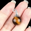 Tiger eye stone ball pendant with silver wizard hat cap shown on fingertips - Tiger's Eye