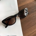 Retro black cat-eye sunglasses with dark lenses on vintage newspaper background - Black Frame Tea Lens