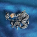 Détail d'une broche dragon argentée avec perle ambrée sur tissu satiné bleu foncé - Dragon Vintage Avec Perle d'Ambre