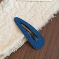 Dettaglio del fermaglio per capelli in denim blu con texture e struttura metallica - goccia