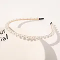 Detailed close-up of a slim gold metal headband with elegant white pearls on a ceramic plate - Single Row Mixed Size Pearls (Medium)