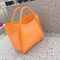 Macro detail of the diamond cutout pattern on a large orange silicone beach tote bag - Orange