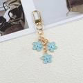 Golden flower keychain featuring three blue enamel floral charms and lobster clasp - Blue