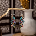 Ethnic peacock drop earrings with colorful rhinestones on a rustic wooden display - Multicolor Rhinestone Enamel Peacock