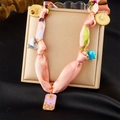 Détail du collier ruban de soie rose avec pendentifs solaires dorés et breloques émail - Émail Soleil Rose (N3609)