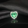 Macro shot of green heart-shaped crystal ring with diamond halo on black satin background - Light Green