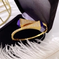 Detailed macro of gold-plated double triangle bangle with blue accents on velvet - Gold + Blue