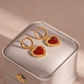 Detalle de pendientes de corazón en esmalte rojo vintage sobre un joyero beige - Aro de Corazón Rojo