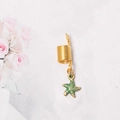 Primer plano de un anillo dorado para rastas con un detallado colgante de estrella de mar - Estilo Estrella De Mar