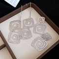 Macro view of silver hammered square spiral necklace and earrings jewelry set on tray - Gold Set