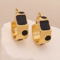 Detail of gold-plated geometric earrings with black enamel pattern on marble base - Black
