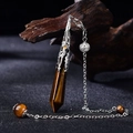 Macro detail of Tiger Eye hexagonal prism pendulum with intricate silver chain on dark wood - Silver Tiger Eye
