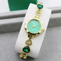 Detailed macro view of heart-shaped gold links with green gems on a ladies watch band - Gold + Green