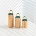 Three gold rings with green gemstones displayed on cylindrical wooden stands - Three-Piece Set / Green Velvet Plane 3-Piece Set