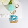Letter B resin keychain with blue stones, gold glitter, and turquoise faux fur pompom - Letter B