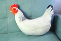 Primer plano de un cojín de gallo de peluche en sofá azul con cresta roja y textura - Pollo Blanco