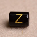 Macro shot of a black resin bead with a gold engraved letter Z for DIY jewelry making - Letter Z