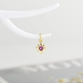 Detailed close-up of a golden star pendant with a centered pink zircon on a white stand - Gold with Rose Red Zirconia