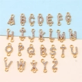 Macro view of 26 gold alloy alphabet pendants with rhinestones on a dual-tone background - Rhinestone Alphabet Set (DY147) / Set of 26 / Style 75 Double Loop Full Rhinestone KC Gold