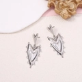 Macro shot of silver heart drop earrings on a vintage aesthetic background textures - Silver
