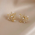 Detalle de pendientes de estrella con perlas y circonitas sobre fondo de seda suave - Pendientes de fuegos artificiales de estrellas doradas (pin de plata S925)