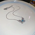 Detailed macro of silver butterfly pendant with zircon crystals and light blue cat-eye stone - Silver Hollow Butterfly Pendant Style / Silver