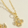 Vue macro du pendentif fleur à quatre feuilles doré avec zircons pavés et chaîne fine - Fleur Creuse