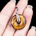 Handheld tiger eye stone donut pendant with silver clasp on a black background - 20mm Tiger Eye