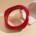 Nahaufnahme eines roten Acryl-Armreifs in unregelmäßiger Form auf Steinsockel - Roter Verdrehter Stil