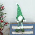 Nahaufnahme von grünem gestricktem Weihnachtswichtel mit gestreiften Beinen auf einer Holzbox - Gestrickter Stil / Sitzen 45cm / Grün