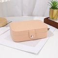 Detail of light pink faux leather jewelry box with white stitching and metal snap button - Khaki