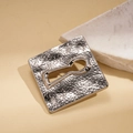 Primer plano detallado de un broche cuadrado plateado con textura martillada y ojo de cerradura - Plateado