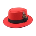 Detailed close-up of red wool pork pie hat with black ribbon and feather embellishment - Red