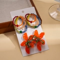 Detail van gekleurde harskralenringen en oranje bloemenoorknopjes op displaykaart - Zilveren Pin Oranje (4-delige Set)