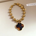 Detail of beaded stainless steel bracelet with clover pendant and tortoiseshell texture - Clover Pendant Beaded / Gold-Tortoiseshell