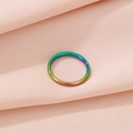 Top view of a minimalist rainbow titanium ring on a textured fabric background - Colorful