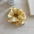Close-up of yellow striped scrunchie with logo tag on a white stone background - Yellow Plaid