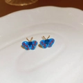 Detalle de pendientes de mariposa azul con cristales rojos y acabados dorados - Diseño de Mariposa / Azul/Rojo/Oro (Con Pin de Plata S925)