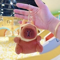 Close-up of plush capybara keychain with yellow hood and golden metal lobster clasp - Dragon Horn Hat Dark Brown + Gold Clip