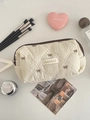 Quilted cream makeup bag with brown bow embroidery and zipper closure shown from above - Coffee Bow Octagonal Bag