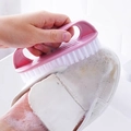 Roze wasborstel met witte borstelharen die een witte canvas schoen reinigt met schuim - Groot / Roze