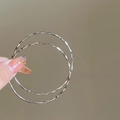 Dettaglio di grandi orecchini a cerchio d'argento intrecciati tenuti in mano per scala - Perno in Argento-Argento-4cm