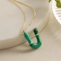 Dettaglio macro della collana placcata oro con ciondolo a forma di U in smalto verde - Lettera U