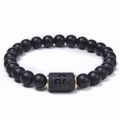 Dettaglio di perle di onice nero opaco e charm dorato del segno Leone sul bracciale - Leone (Leo)