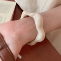 Primer plano de un brazalete de resina acrílica crema ondulado puesto en la muñeca - Brazalete irregular ondulado / Blanco Roto