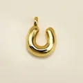 Polished gold horseshoe pendant in a minimalist 3D design on a creamy background - Letter U