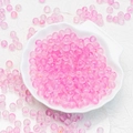 Macro shot of 6mm pink frosted glass beads with glitter in a white shell dish for DIY jewelry - 8mm Pink with Gold Glitter