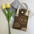 Detail shot of a brown knitted phone bag with cute cartoon sheep and cloud patterns - Little Lamb Khaki