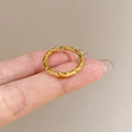 Golden open twist ring with twisted rope texture shown on hand in warm beige setting - Twisted Rope